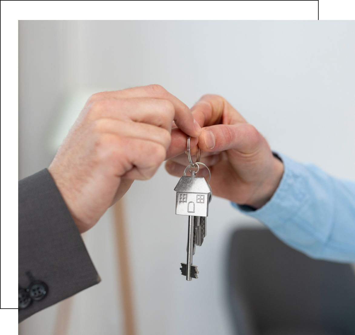 Two people exchanging keys with house keychain.